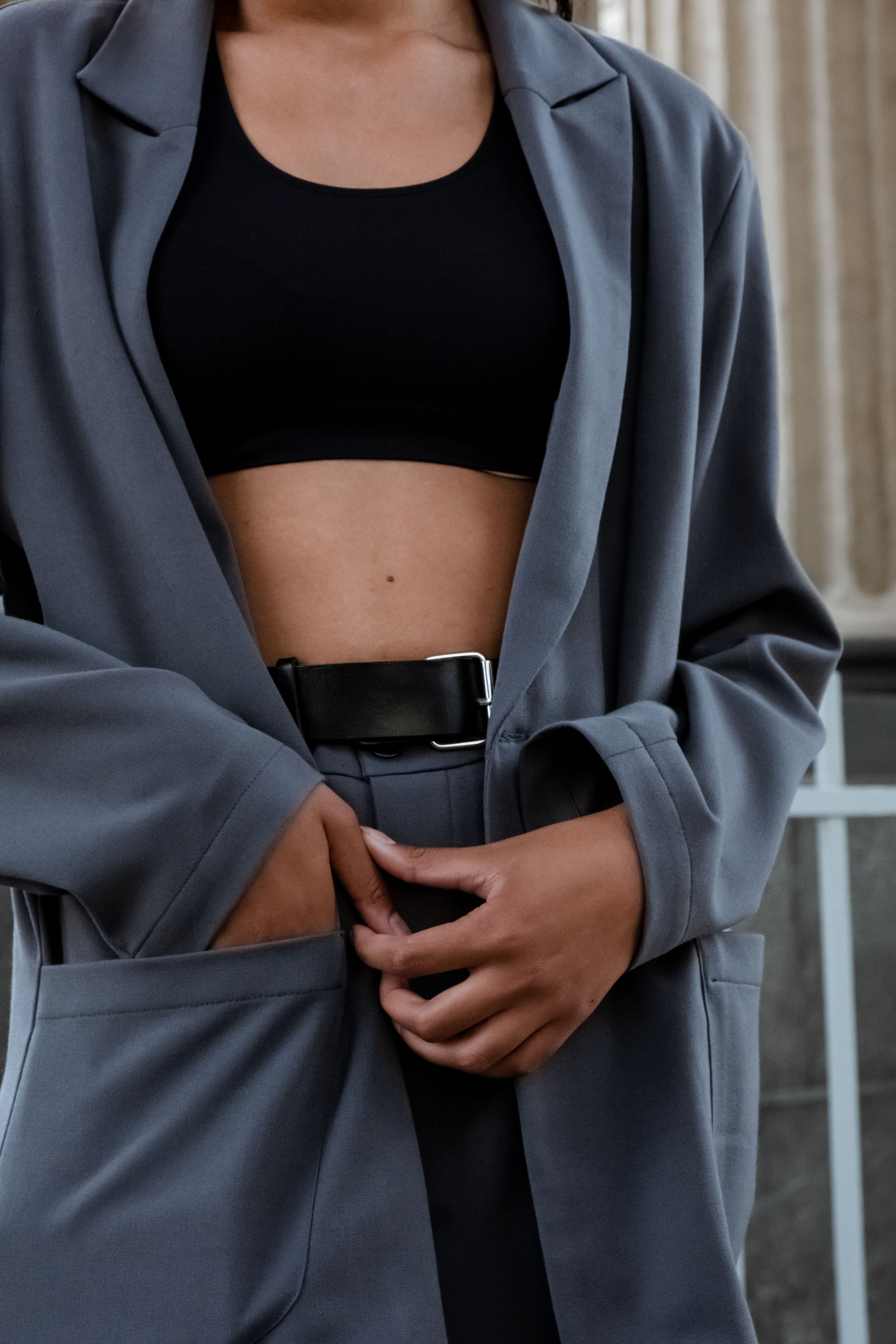 Close-up de uma mulher estilosa com um blazer cinza, exibindo um estilo moderno.