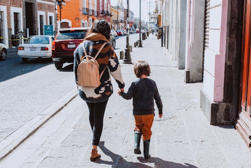 Mother with Child Walking along Sidewalk