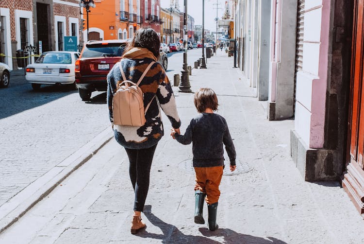 Mother With Child Walking Along Sidewalk