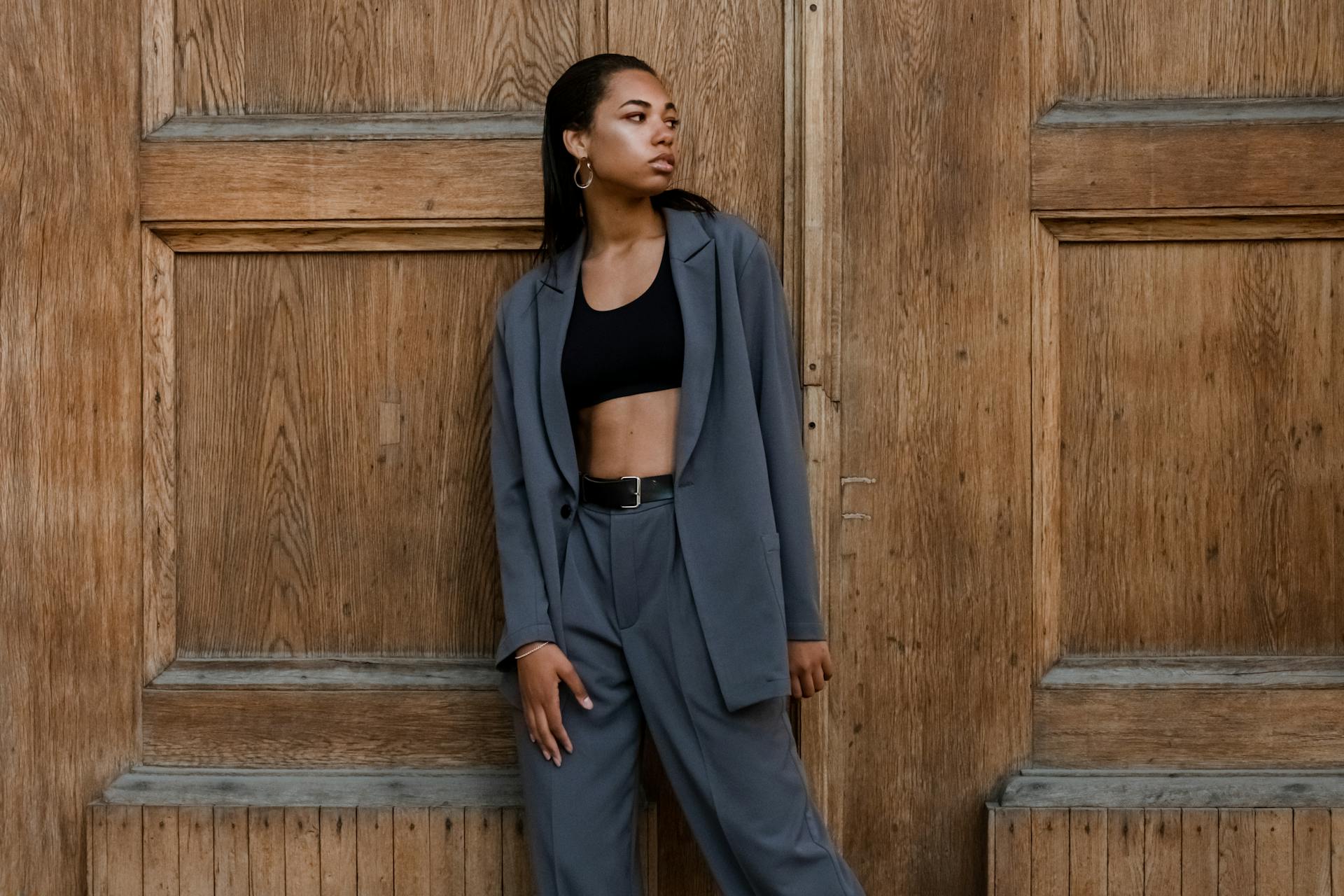 Woman in Black Tank Top and Gray Blazer Standing Beside Brown Wooden Wall