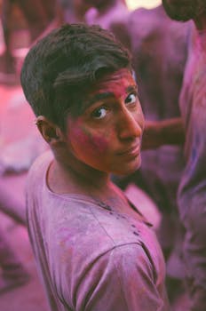Young man covered in colorful powders during Holi festival in Pushkar, India.
