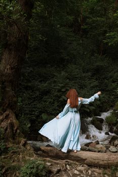 一位身着浅蓝色连衣裙的女子，赤足静立在平静的森林溪流边，尽显宁静