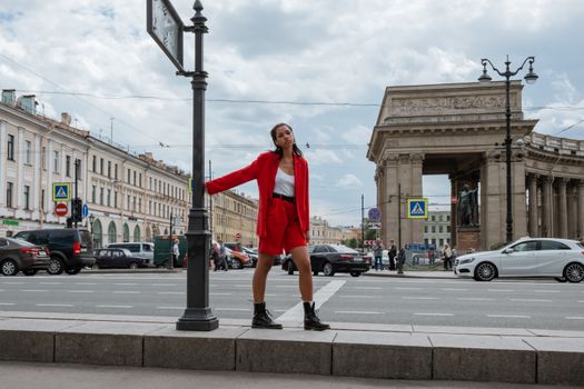 Stylish woman in red suit poses on Nevsky Prospekt with Saint Petersburg architecture.