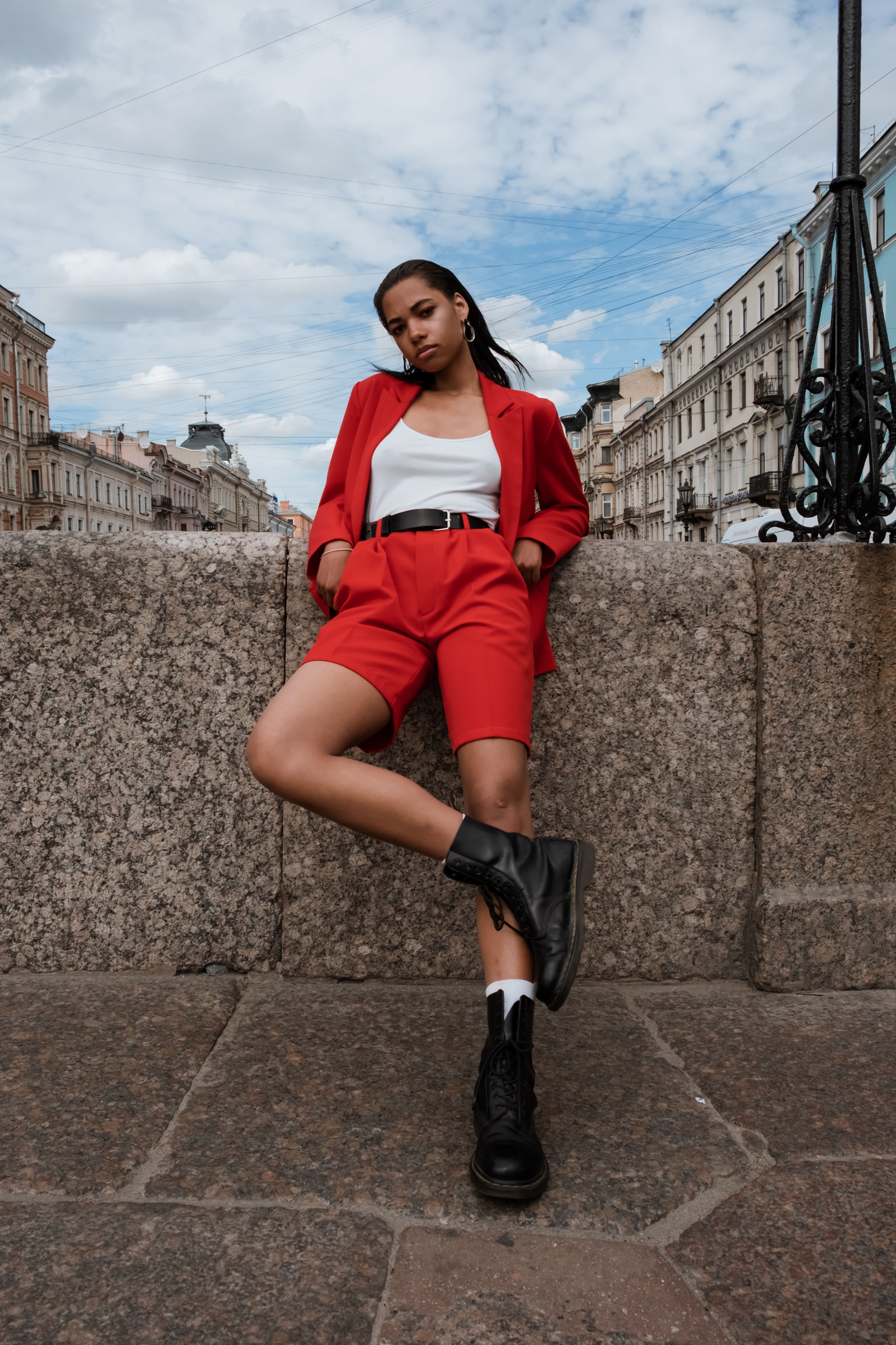 Mulher estilosa em traje vermelho posa contra o cenário urbano, exalando confiança.
