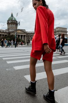 Model in red suit crossing street by Kazan Cathedral, St. Petersburg.