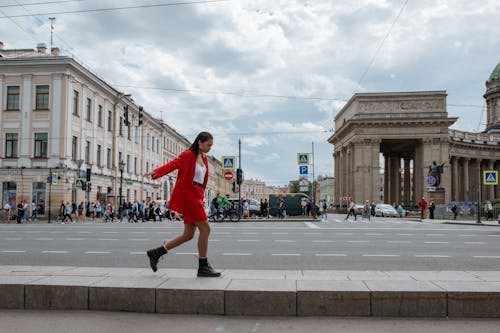 Woman in Red Jacket and Black Pants Running on Street