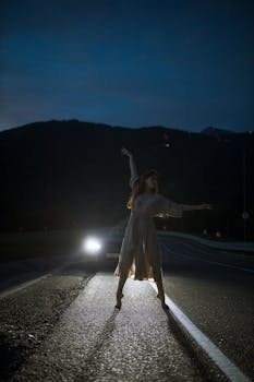 在夜间被汽车前灯照亮的道路上，女人优雅地跳舞