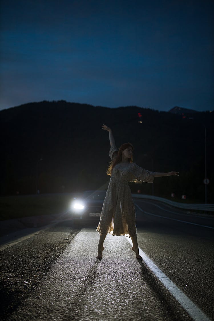 Photo Of A Woman Dancing On A Road During The Night