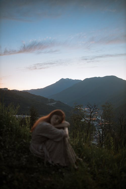 Woman Sitting on the Ground in the Mountains