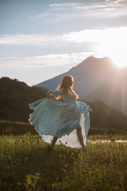 Woman in Blue Dress Standing on Green Grass Field