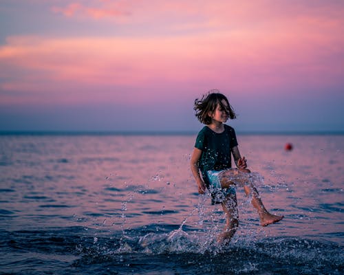Glad girl jumping in water of sea
