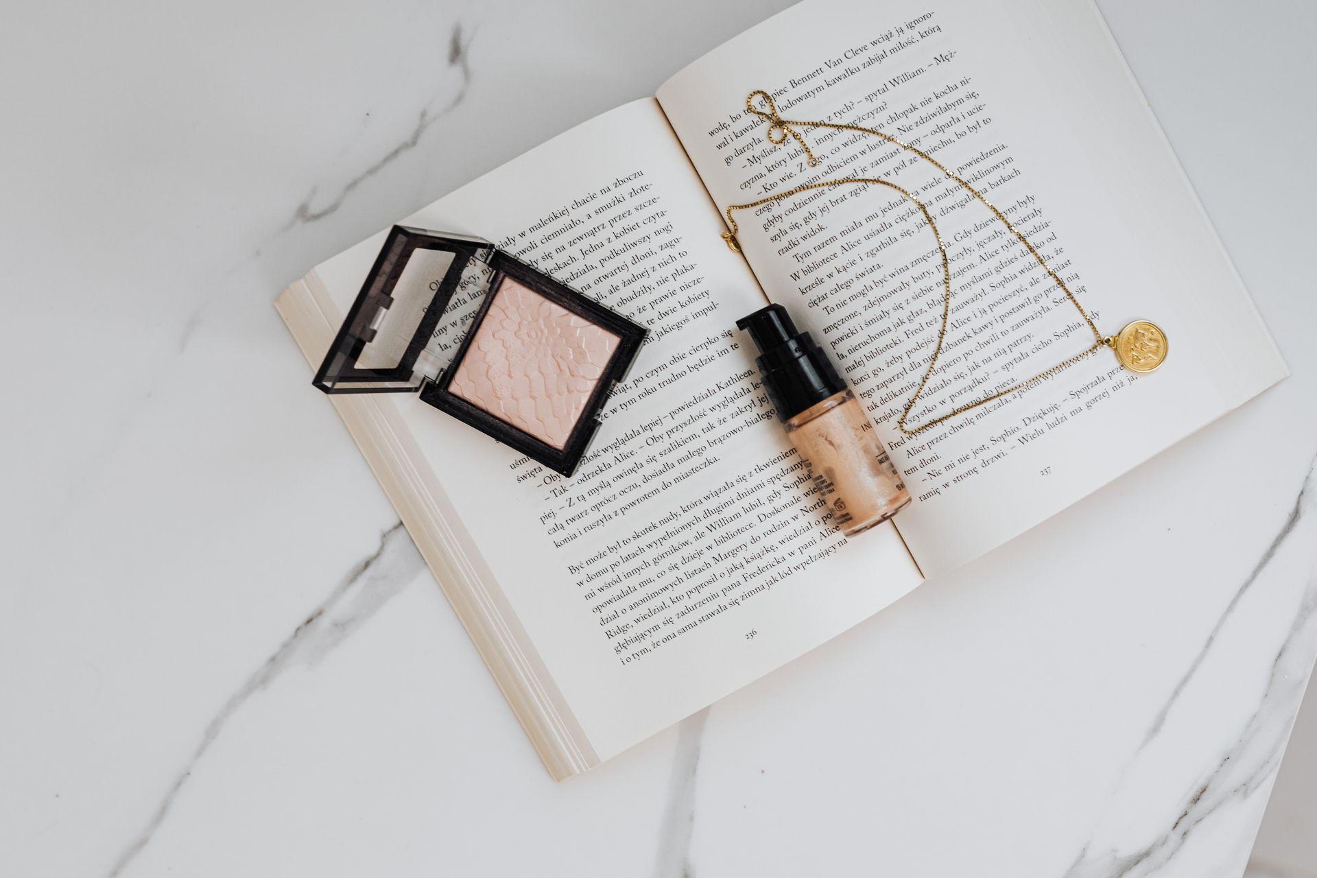 Elegant flat lay of beauty products and jewelry on an open book for a chic lifestyle aesthetic.