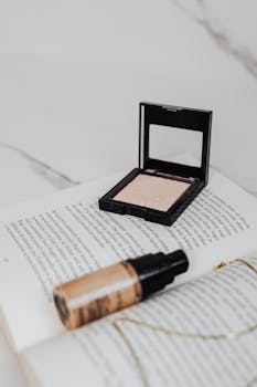 A flat lay of cosmetics including foundation and powder on an open book.