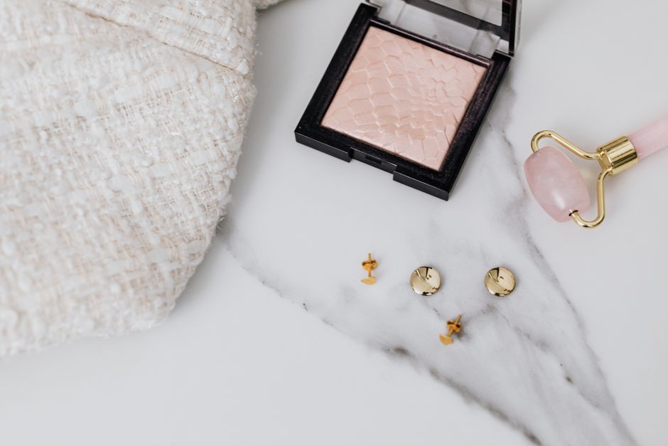 Symbolic jewelry pieces — hamsa, lotus, and crescent moon pendants arranged on white marble surface
