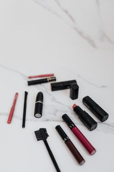 A stylish flat lay of assorted makeup items on a marble surface, showcasing lipstick and brushes.