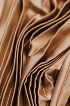 Close-up of elegant brown satin fabric with intricate folds and soft texture.