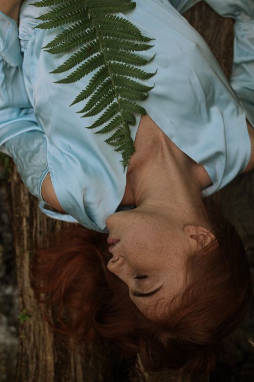 Free An artistic upside-down portrait of a woman with a fern leaf in a natural setting. Stock Photo