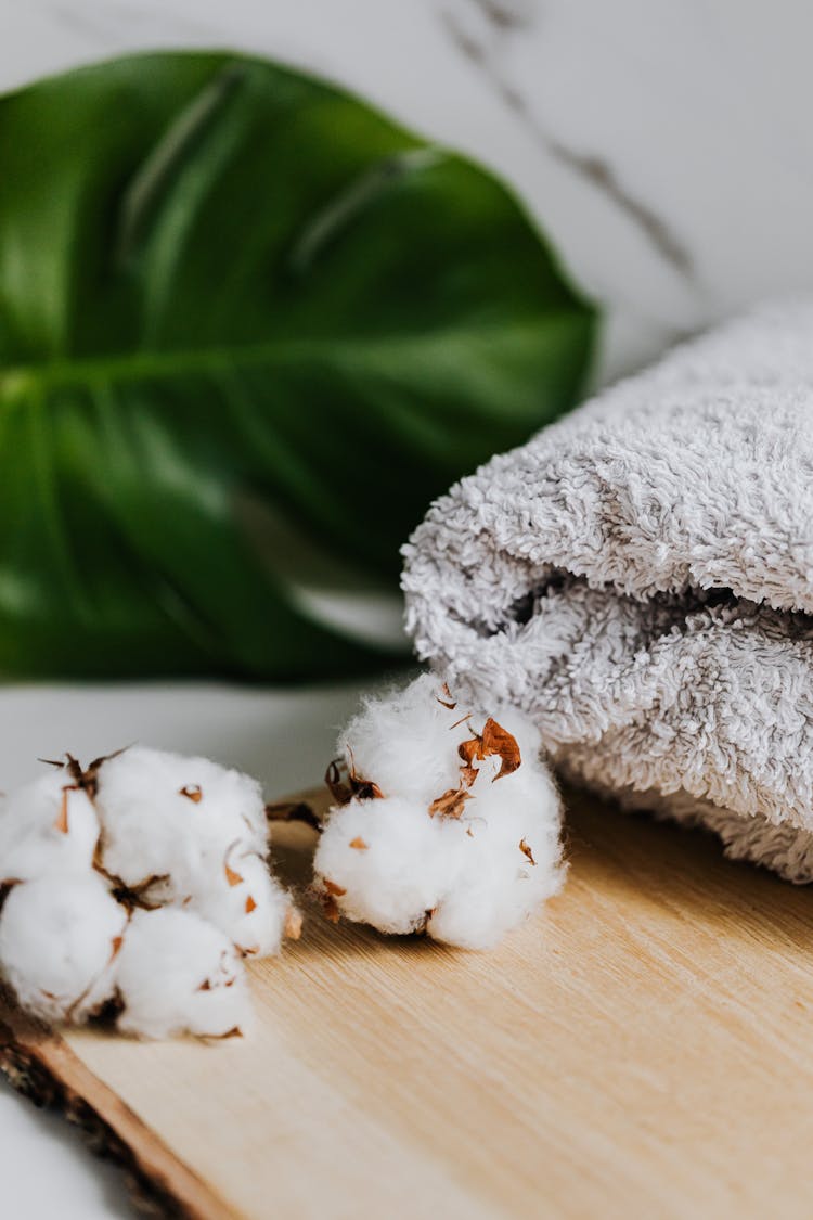 Cotton Flowers Near Towel On Brown Wooden Board