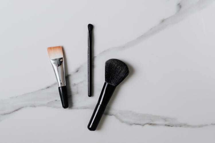 Overhead Shot Of Makeup Brushes On A Marble Surface