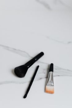 A close-up of makeup brushes on a marble surface, ideal for beauty and cosmetic themes.