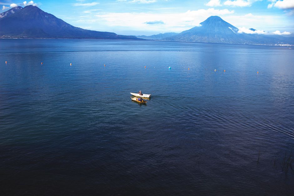 Tranquil scene of a boat on Lake Atitlán, Guatemala with mountains in the background.