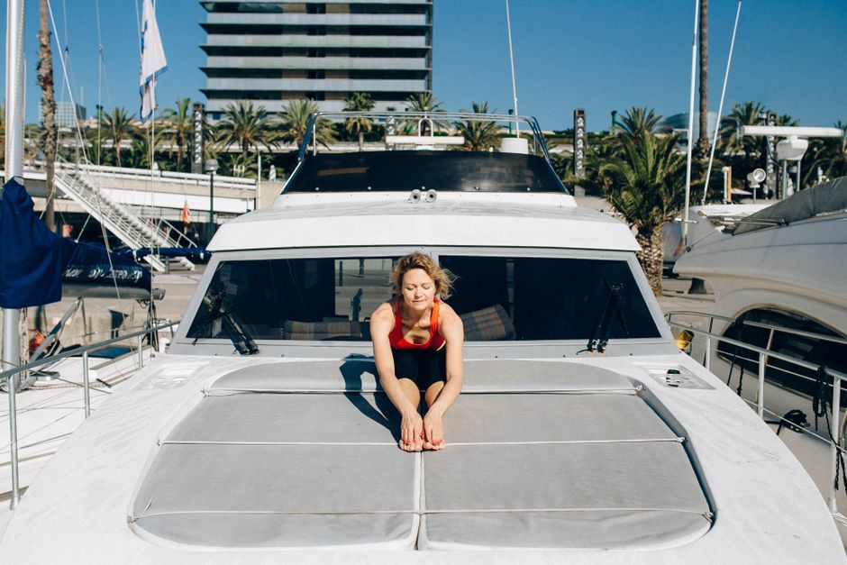 A woman doing yoga on a yacht in a sunny marina, representing luxury and relaxation.