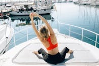 在宁静的码头上，女人练习瑜伽，在游艇上伸展，以此促进健康的生活方式