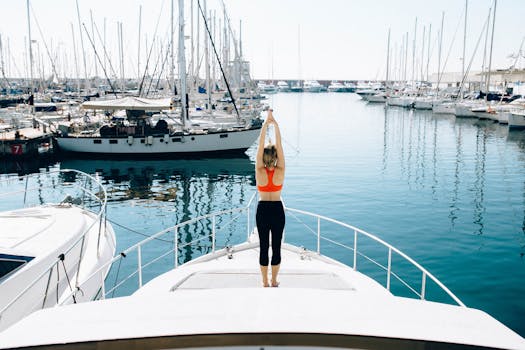 A woman stretches on a yacht deck surrounded by water and boats in a marina.