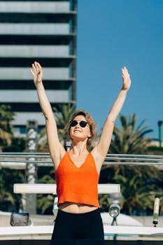 Confident woman stretches under clear sky in urban setting, embracing sunny day.