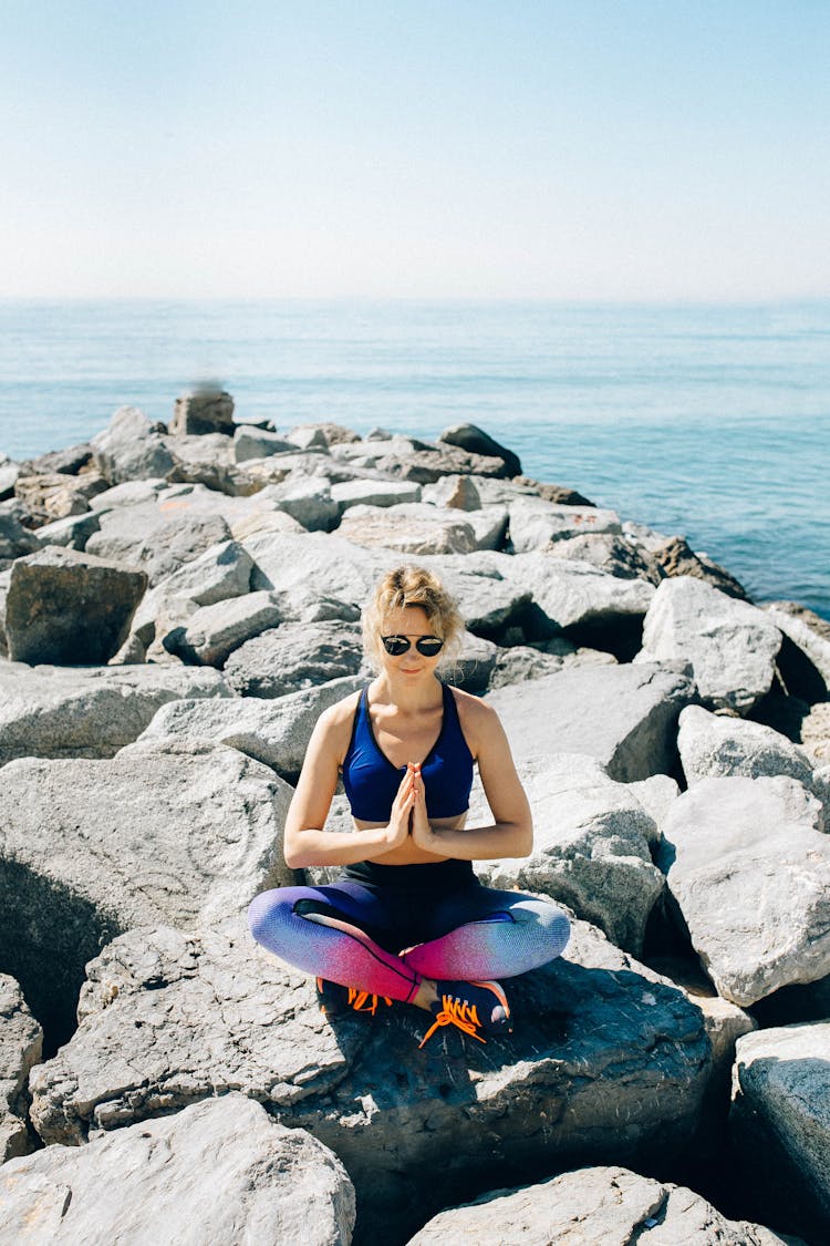 Woman Meditating On A Rock By The Sea