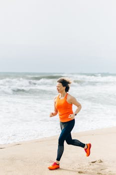 Caucasian woman jogging on the beach in orange tank top, embodying active lifestyle and fitness.