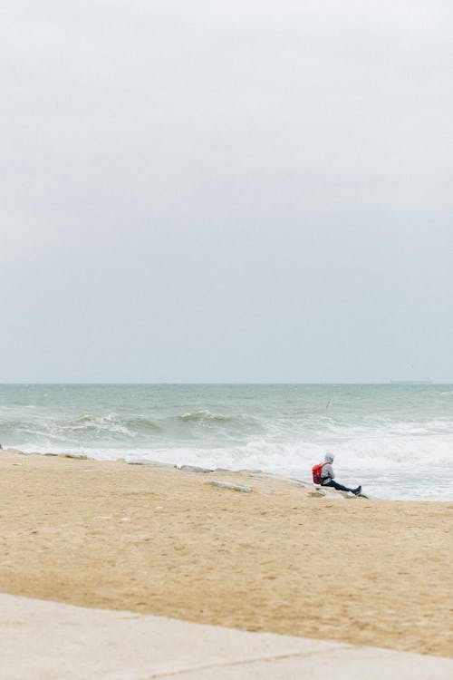 Photo of a Person Sitting Alone on a Beach