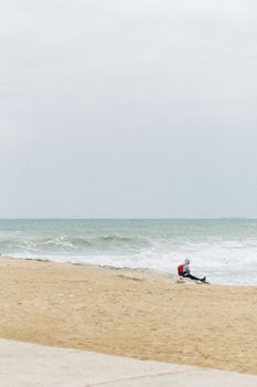 海浪旁的沙滩上，一个孤独的人坐着，一派宁静的景象