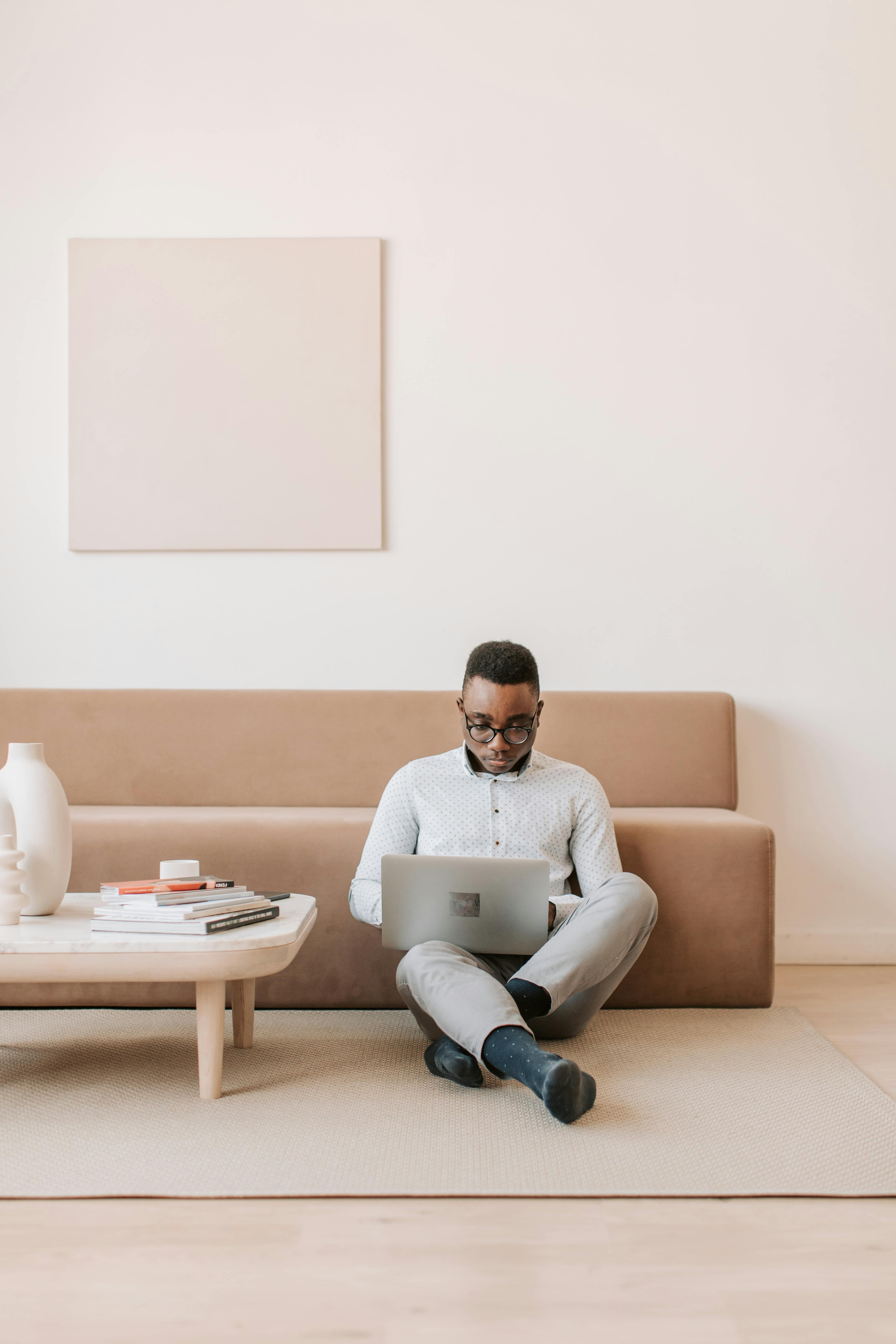 man sitting on the floor and working on his laptop