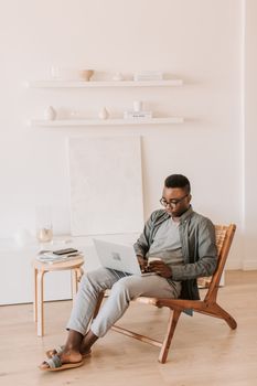 A man comfortably sits at home working on a laptop, showcasing a modern work-from-home lifestyle.
