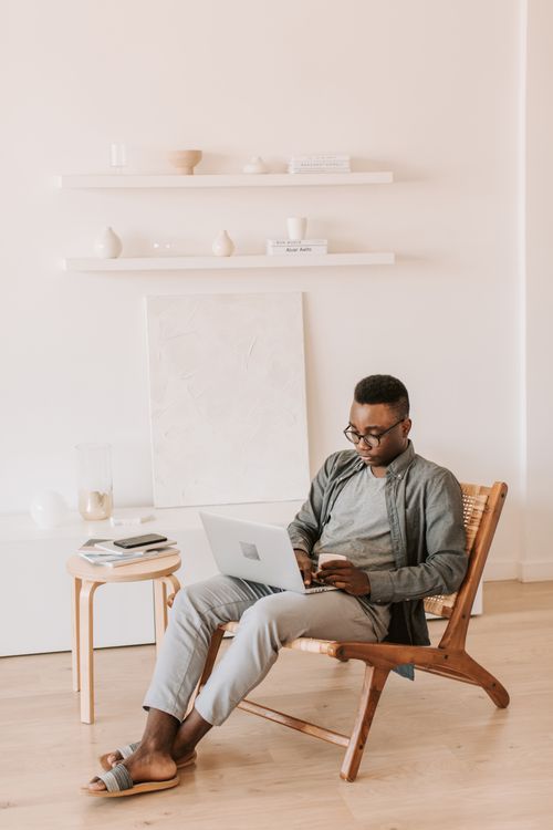 Free A man comfortably sits at home working on a laptop, showcasing a modern work-from-home lifestyle. Stock Photo