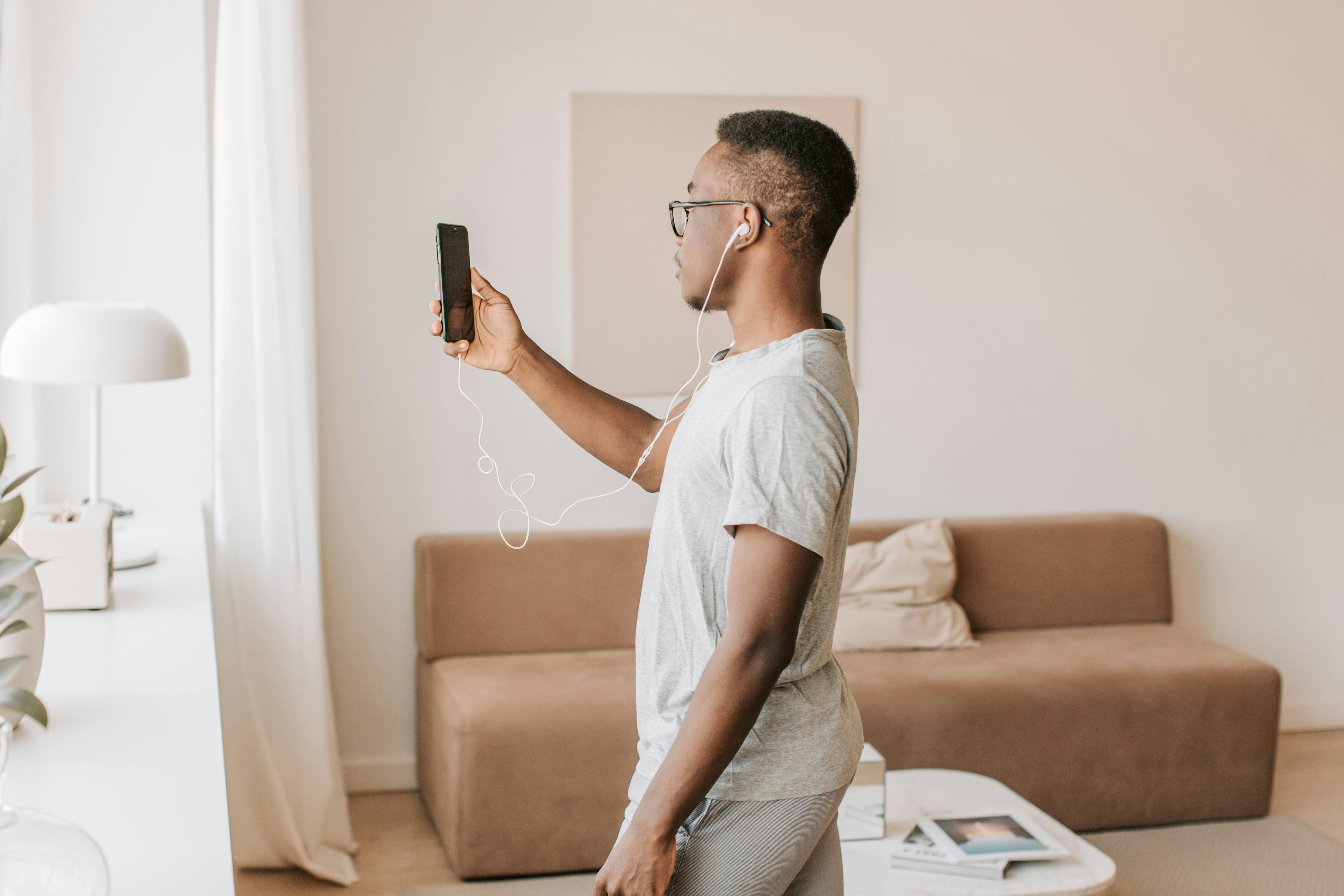 a man in gray shirt using a cellphone with earphones