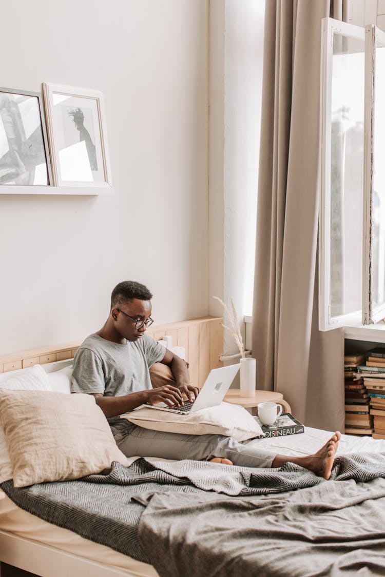 Man Sitting On Bed With His Laptop