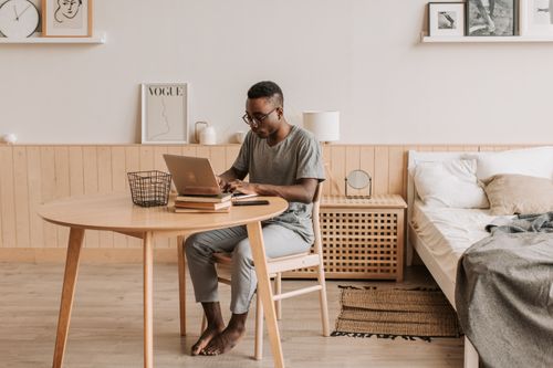 Free Man working remotely from home using laptop. Cozy and minimalist workspace. Stock Photo
