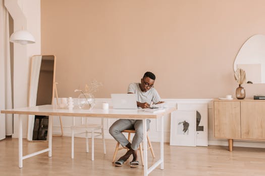 Man working on a laptop at a modern home office with minimalist design and decor.