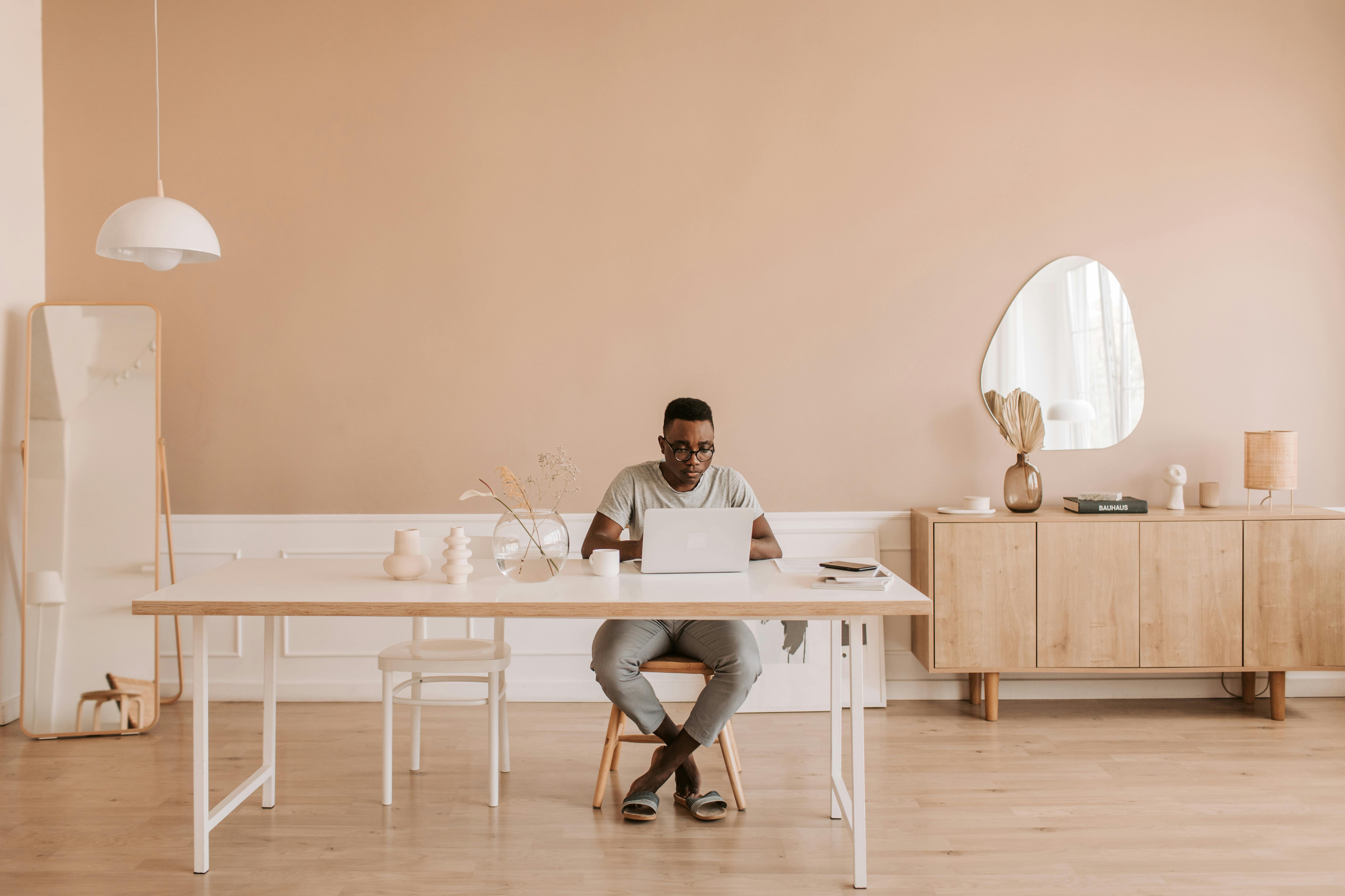 Man working remotely on a laptop in a minimalistic, stylish home office setting.