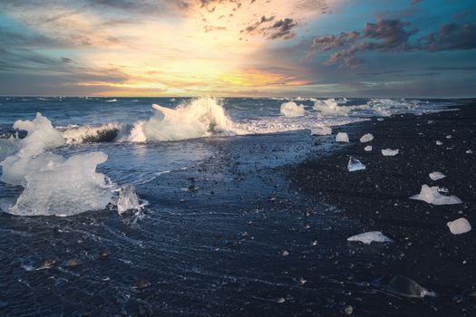 Stunning view of Iceland's coast with ice formations and a vibrant sunset.