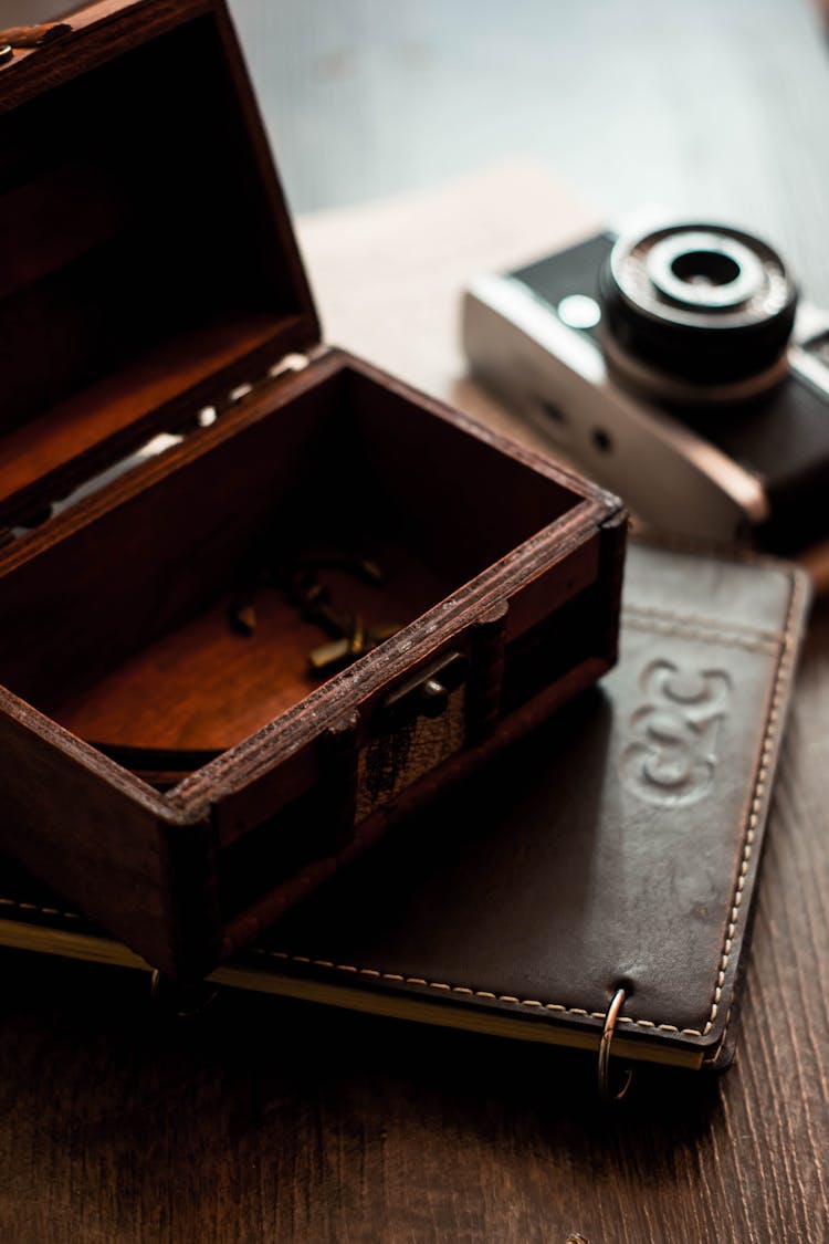 Old Photo Camera Arranged On Table With Vintage Chest And Notepad