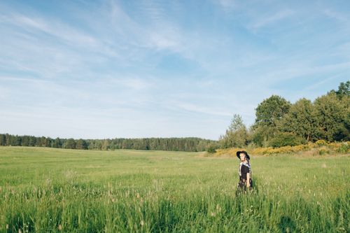 Free A woman in a black dress enjoys the open countryside under a bright summer sky. Stock Photo
