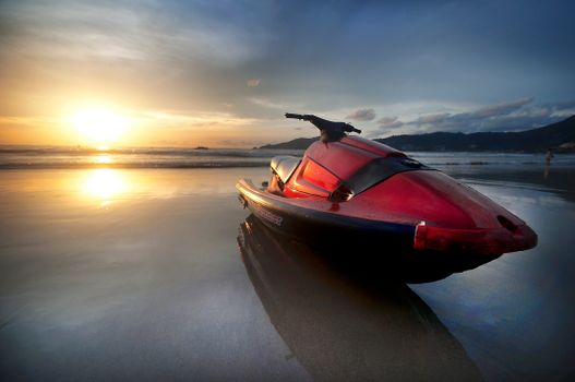 Stunning sunset over Phuket beach with a jet ski reflecting in the water.