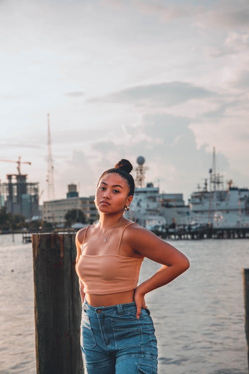 Woman in Beige Crop Top Standing on Dock During Sunset