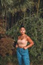 Young Woman in Crop Top and Jeans Standing Beside Bamboo