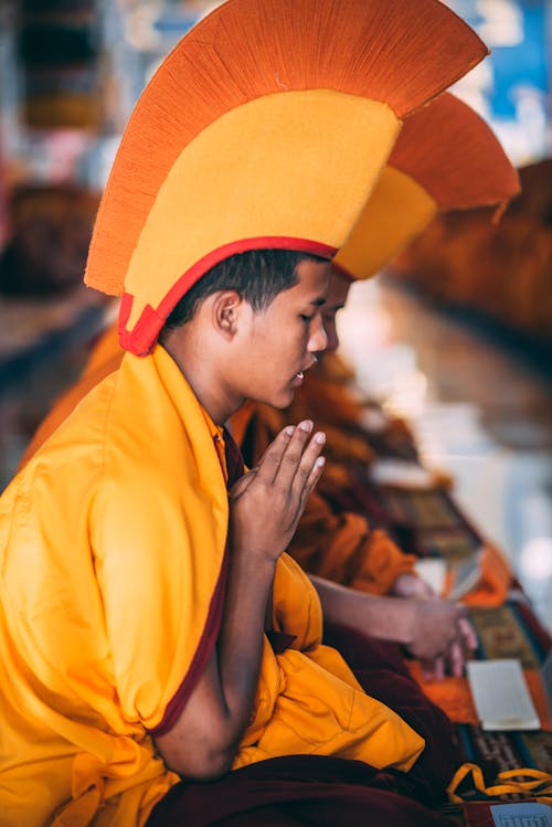 A Close-Up Photo of a Man in Gelugpa Hat Praying