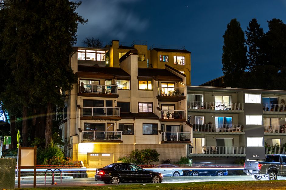 Light streaks from traffic and lit apartments capture a lively urban scene at night.