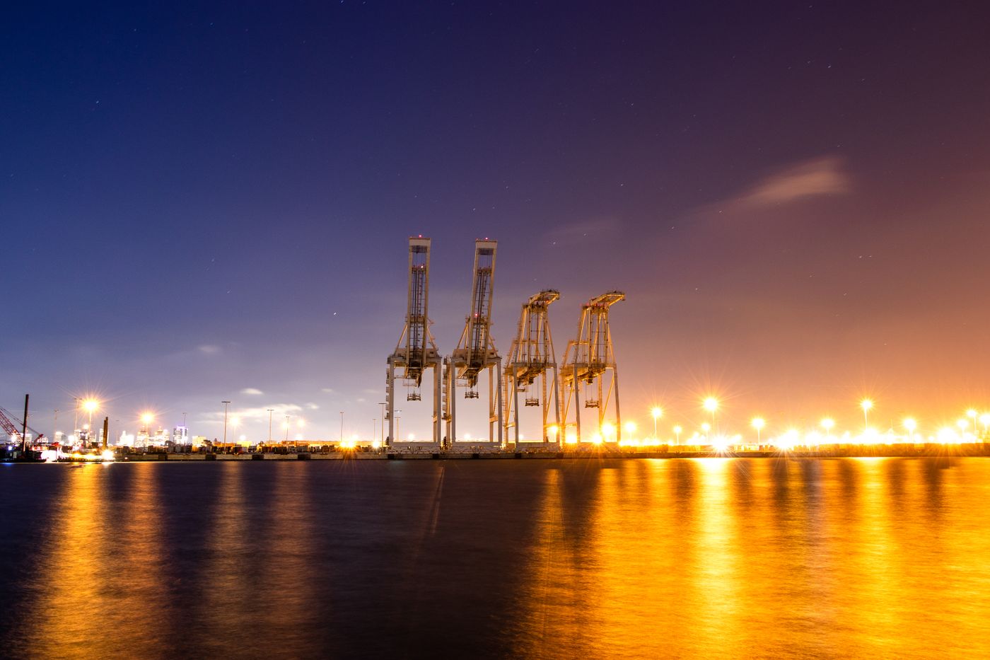 Cargo cranes illuminated at a port at night